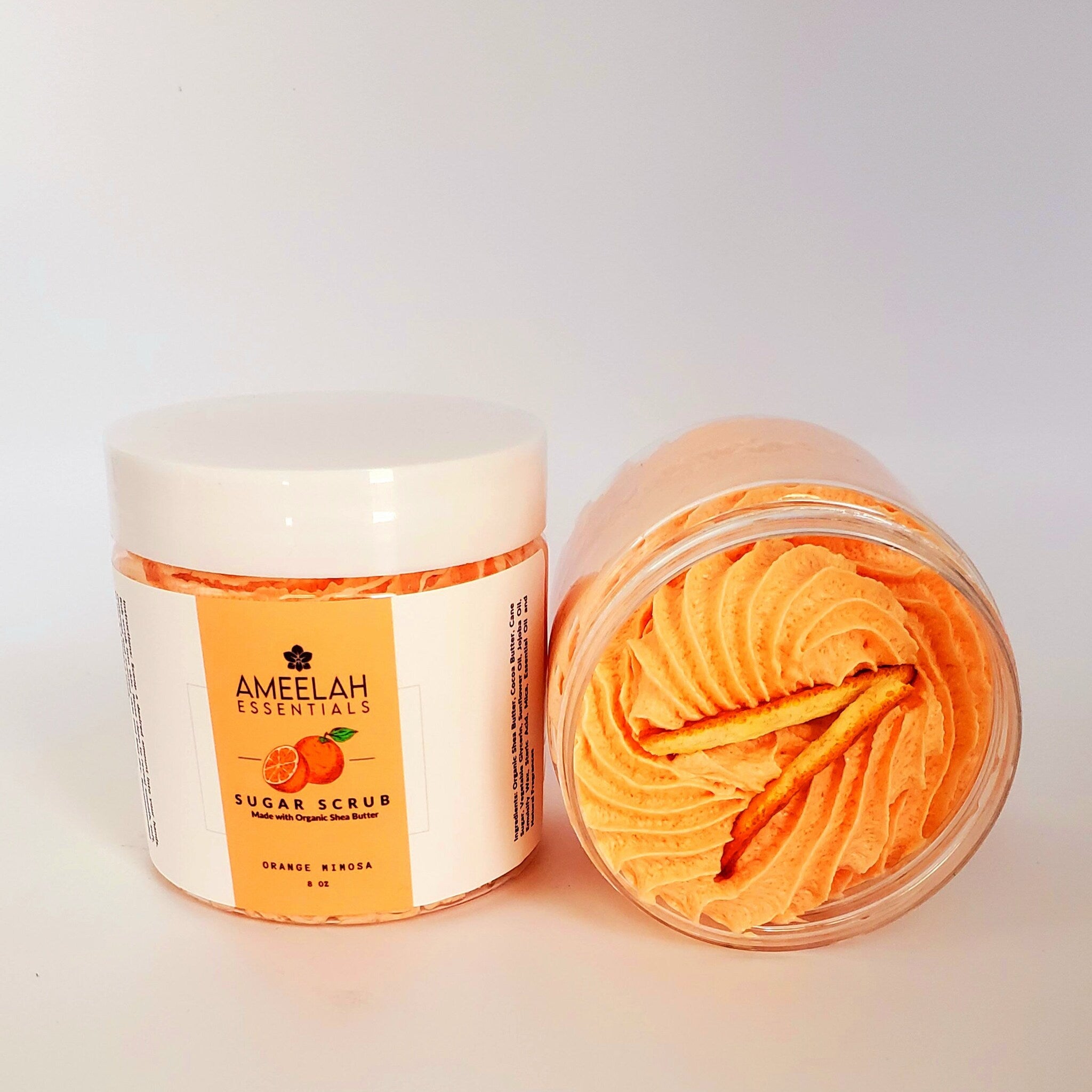 Sugar scrub jar with orange cream, white lid, and Ameelah Essentials label