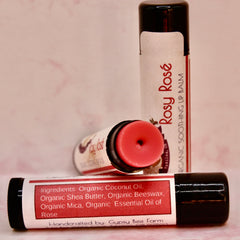 Lip balm tubes with pink balm, black caps, and "Rosy Rosé" label text