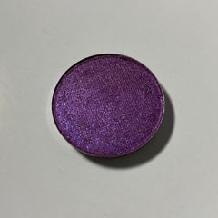 Close-up of fingertips applying shimmery pink eyeshadow to eyelid with soft blending motion