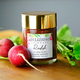 Face scrub jar with gold lid, glass jar, and red radish on wood surface