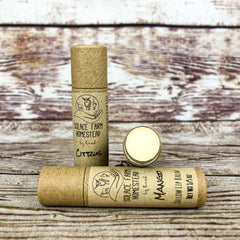 Lip balm tubes, brown cardboard, yellow balm, Solace Farm Homestead brand, citrus and mango flavors shown