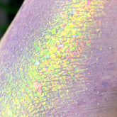 Eye shadow swatch with lavender and iridescent foil pigment, showing texture and color