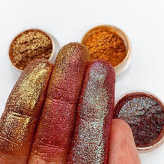 Close-up of loose pink glitter eyeshadow pigment with holographic sparkle in a small open jar
