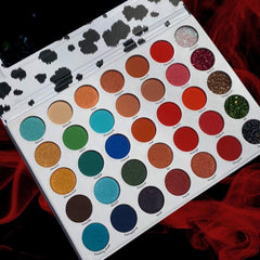Eyeshadow palette with white and black spotted lid, various colorful eyeshadows, and round compacts