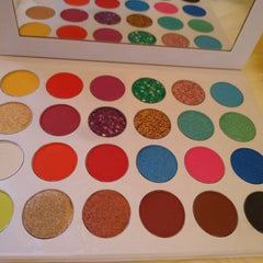 Eyeshadow palette with various colors, including glitter and matte, in a white case