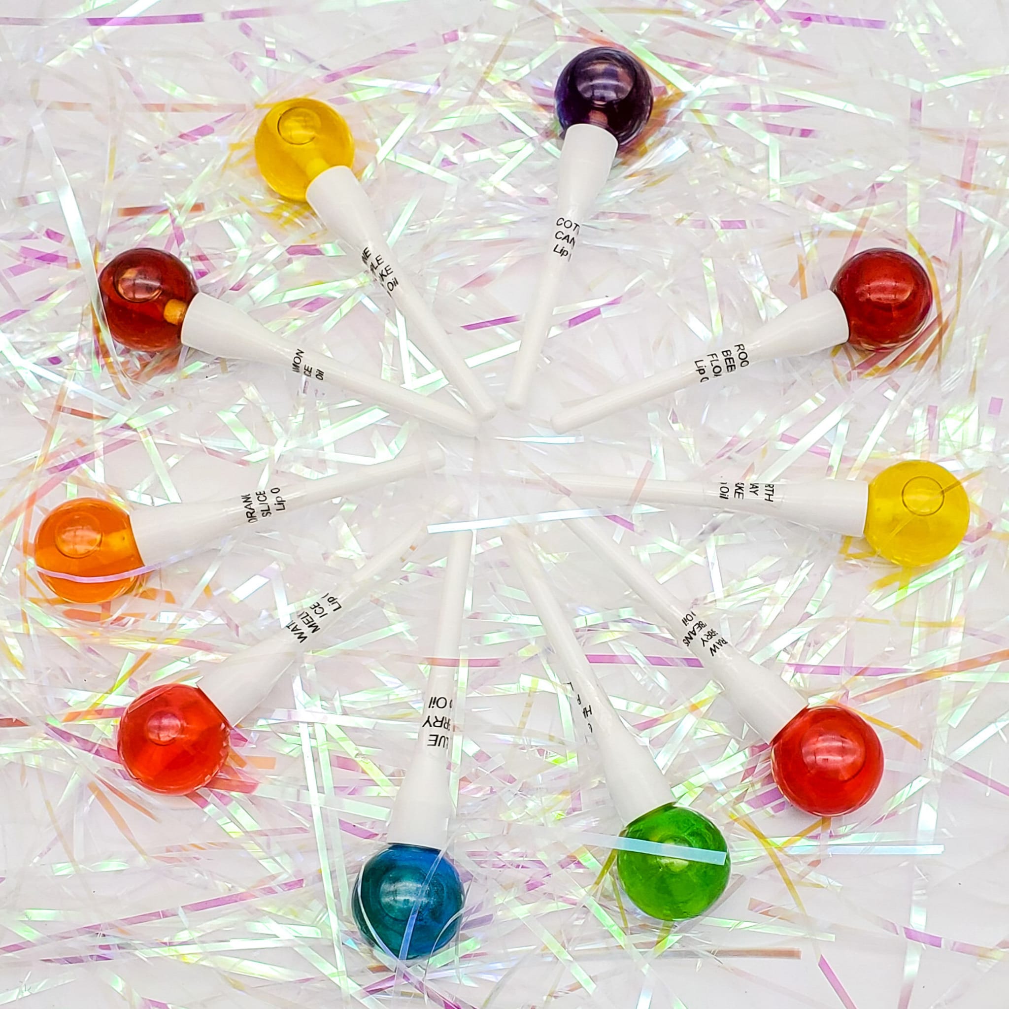 Lip oil & lip scrub duo, colorful lollipop-shaped bottles, white stems, EYESEYE text