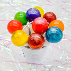 Lollipops in various colors, shiny, round, arranged in a white bucket on a reflective surface