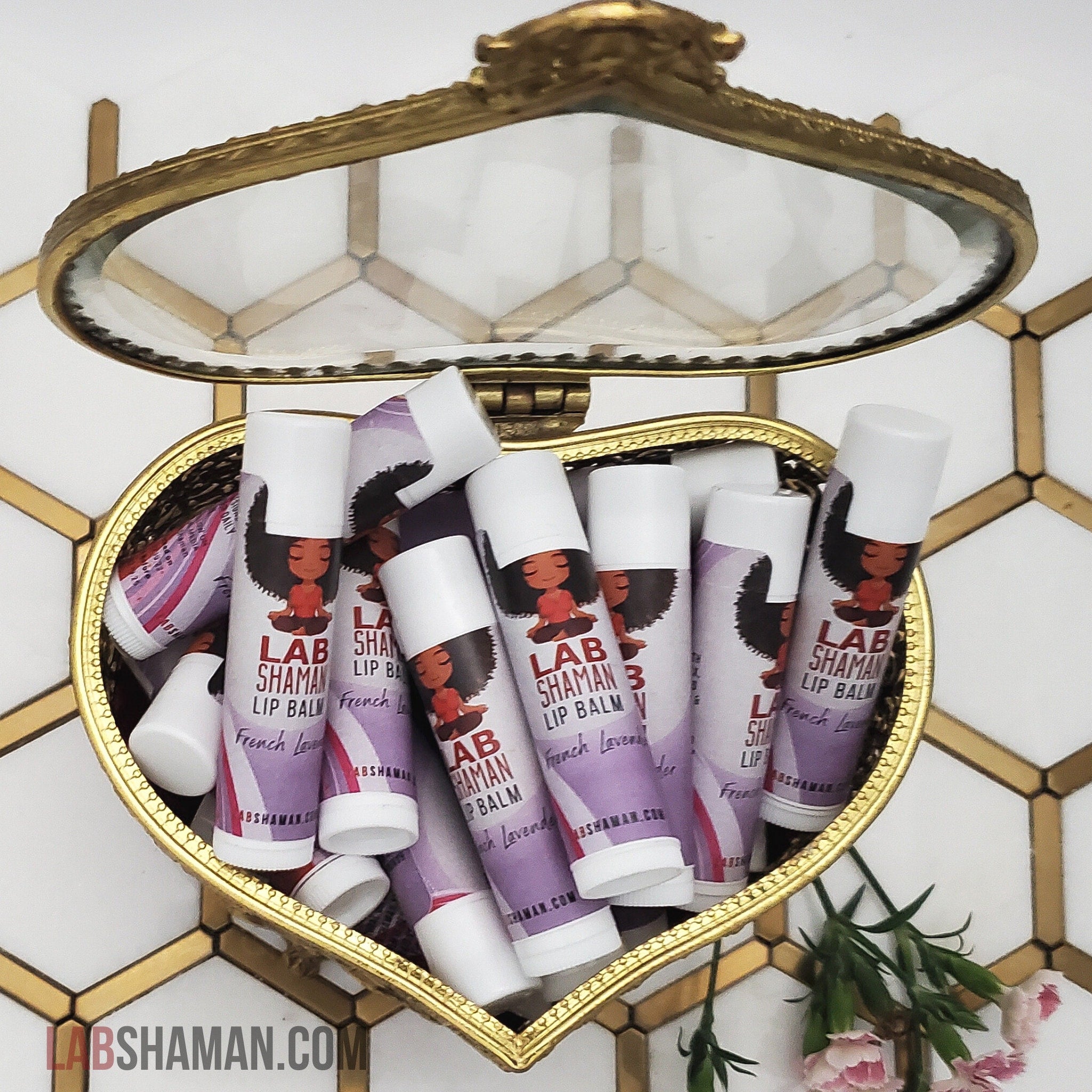 Lip balm tubes with white caps, purple label, in heart-shaped gold container, LAB SHAMAN visible
