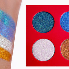 Eyeshadow palette with blue, green, white, and gold shimmer eyeshadows on a red background and arm