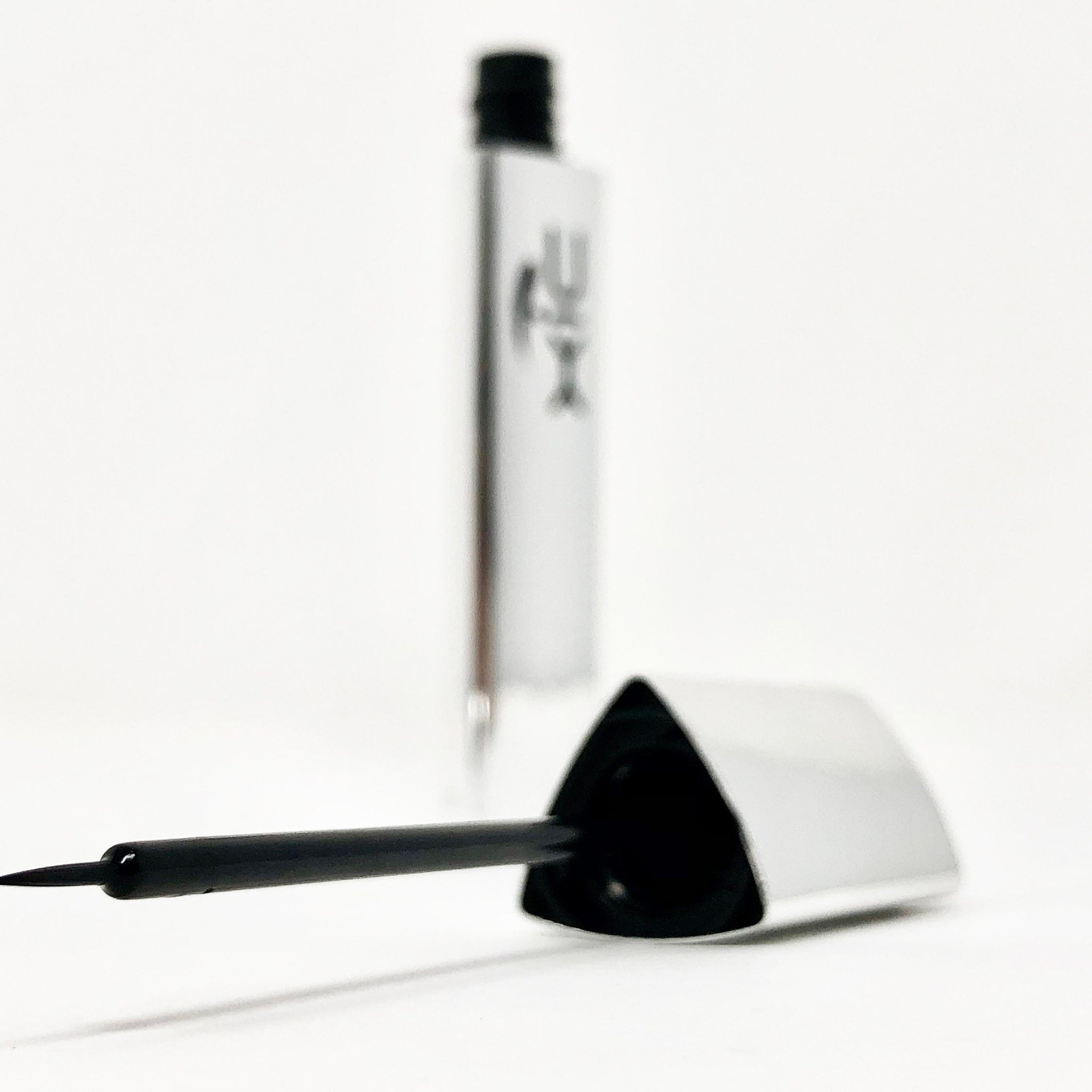 Liquid eyeliner, black applicator with fine tip, silver tube with XiC text visible