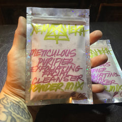 Facial cleanser powder mix in clear iridescent bag with handwritten text, held by hand