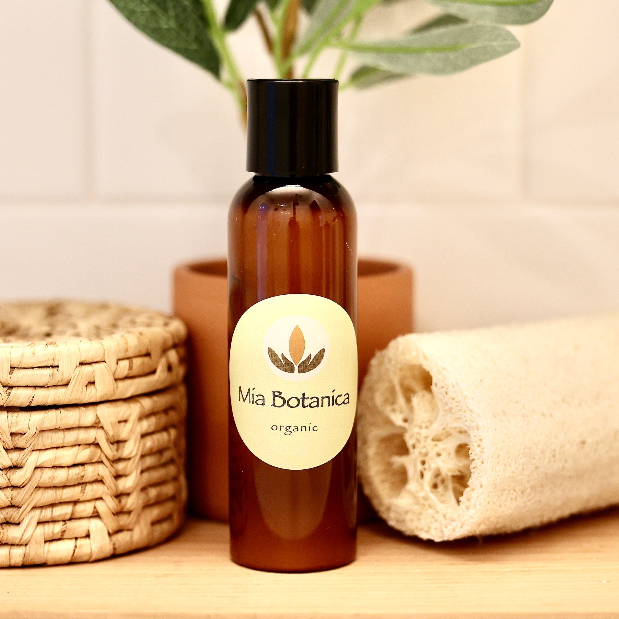 Facial Cleanser bottle brown glass with black cap, Mia Botanica label, on wood surface