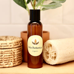 Facial Cleanser bottle brown glass with black cap, Mia Botanica label, on wood surface