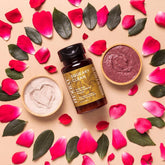 Face powder with pink petals, green leaves, and Ora's Amazing Herbal bottle on beige surface