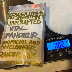 Facial cleanser powder mix in clear plastic bag with gold lettering on scale, reading 0.2 oz