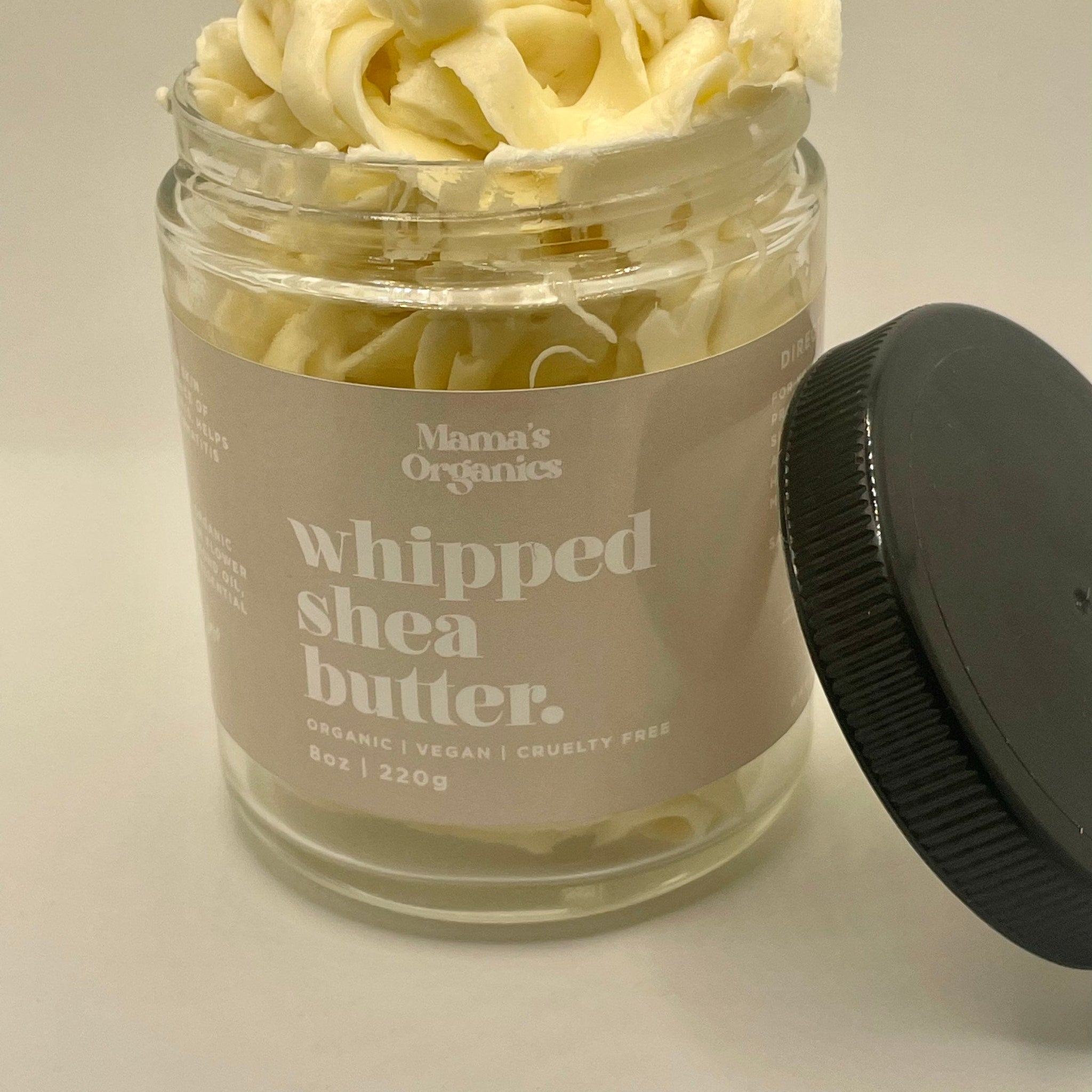 White jar of whipped shea butter with smooth texture and minimalist gold lid, placed on marble surface