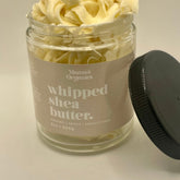 White jar of whipped shea butter with smooth texture and minimalist gold lid, placed on marble surface