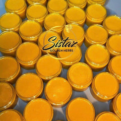 Side view of golden turmeric honey scrub in glass jar with black lid and natural texture visible