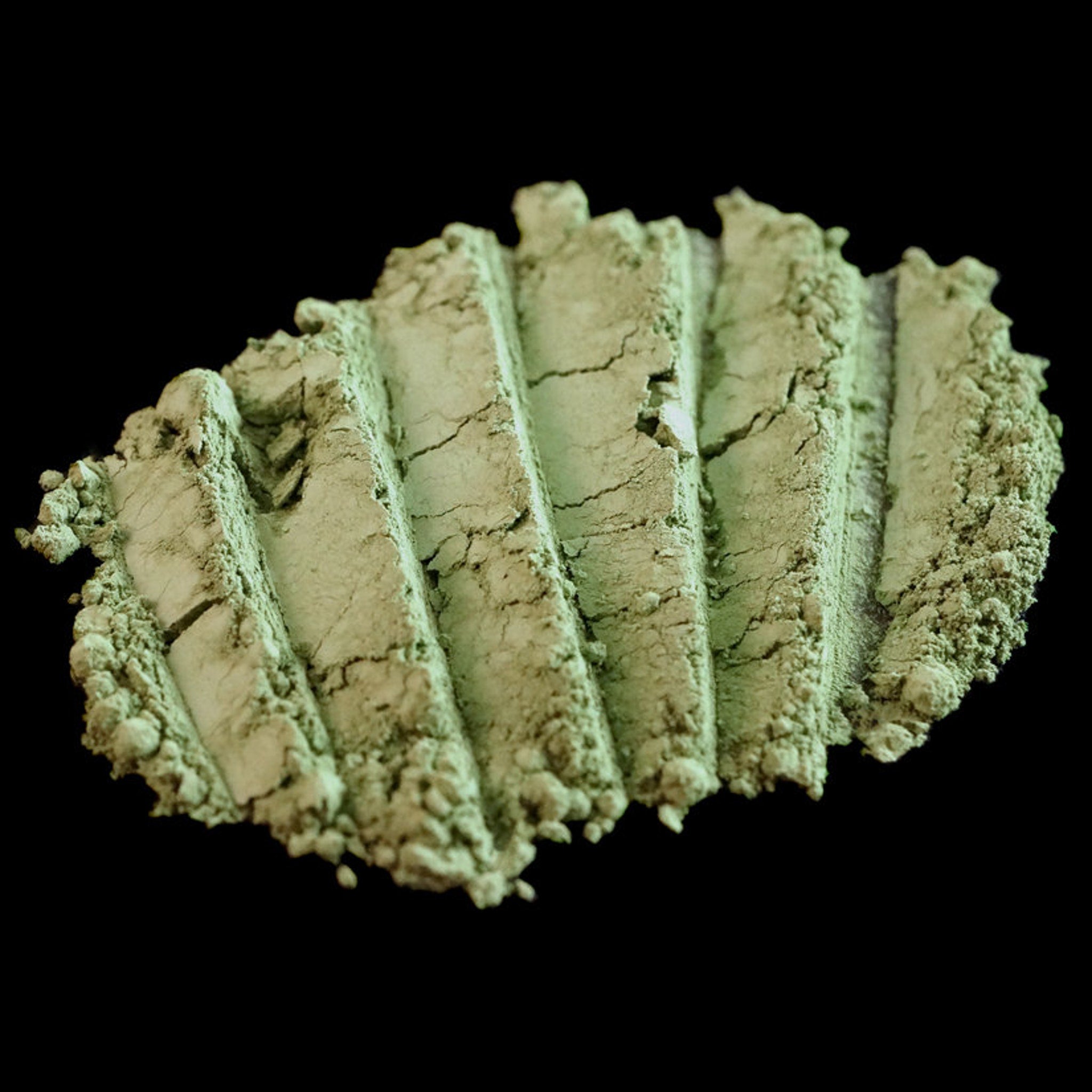 Matte sage green loose mineral eyeshadow in a small jar with gold lid, showcasing the Withered Garden olive shade.