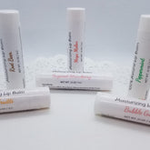 Lip balm tubes, white with various flavor labels, arranged on white surface