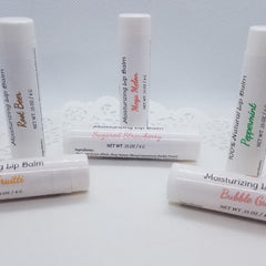 Lip balm tubes, white with various flavor labels, arranged on white surface