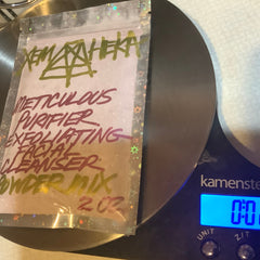 Facial cleanser powder mix in clear plastic bag with green and red text, on scale