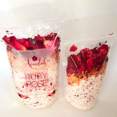 Bath crystals in clear plastic bags with red rose petals, pink salt, and ameelahessentials branding