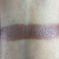 Close-up of makeup brush applying shimmery teal eyeshadow from palette to eyelid