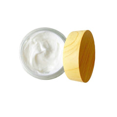 Cream jar with white cream, clear glass, and wooden lid on white background