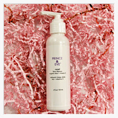 Face cleanser bottle, white plastic pump, pink shredded paper background, PRINCE & EVE text