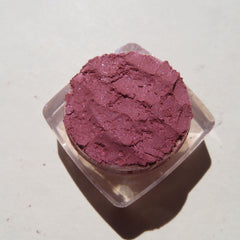 Eye shadow powder in burgundy with glitter, in a clear plastic container, top view