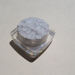 Close-up of loose white and taupe glitter eye shadow pigments with intense sparkle in a set of two jars