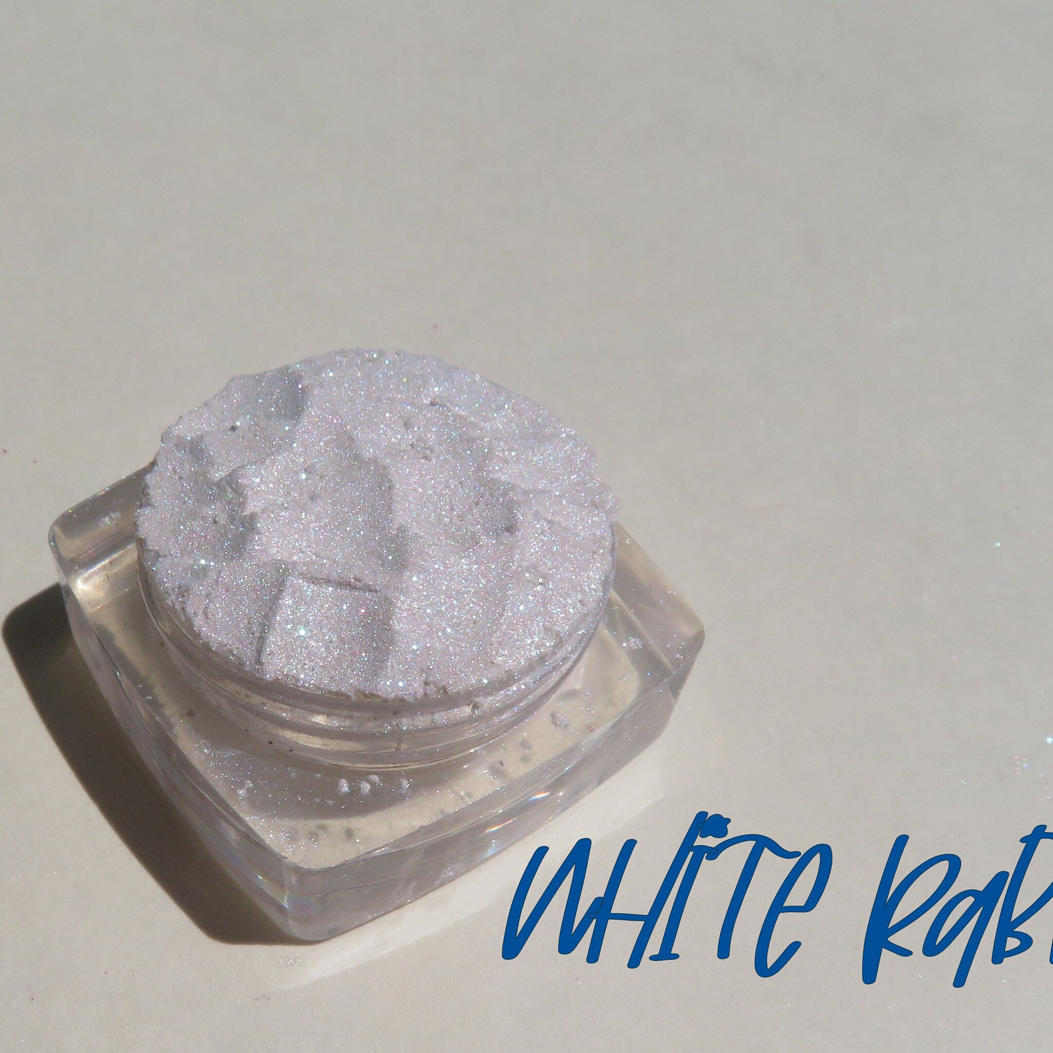 Sparkling white loose eyeshadow with violet shimmer in a round jar, vegan glitter pigment for highlighting