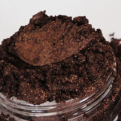 Brown glitter powder with sparkling flecks in glass jar close-up view