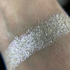 Close-up of hand applying shimmery taupe eyeshadow from palette with a fluffy blending brush