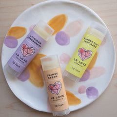 Lip balm tubes in various colors with LB Love branding on a patterned plate