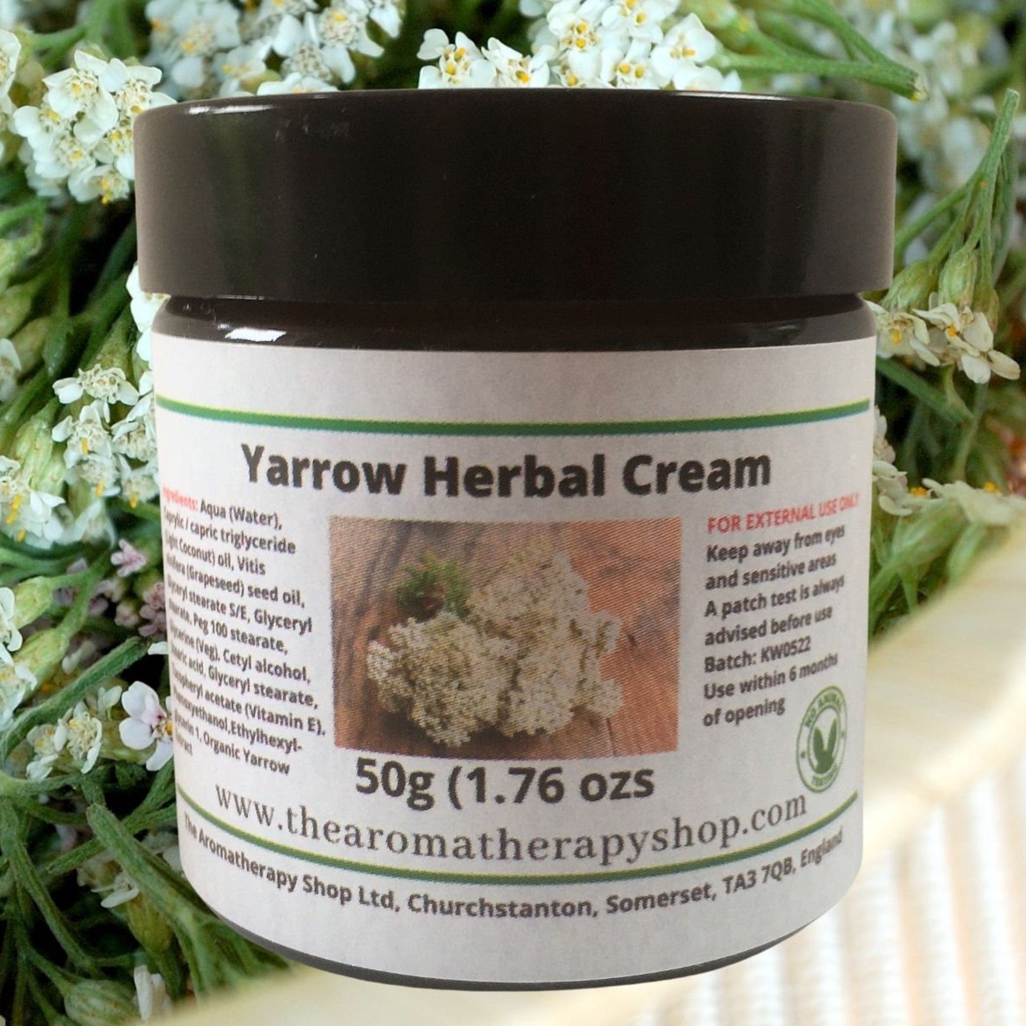 White plastic jar of yarrow herbal cream with minimalist label and gold accents, showcasing rich texture