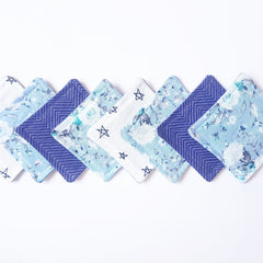 Cloth napkins in blue floral, star, and herringbone patterns on white background