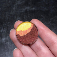 Eyeshadow compact with yellow, orange, and brown metallic colors held in hand