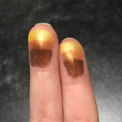 Eyeshadow swatches with gold and bronze metallic colors on fingers for testing
