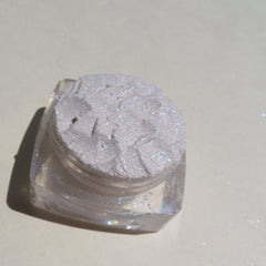 Hand applying sparkly white rabbit eyeshadow with violet shimmer using a fluffy brush