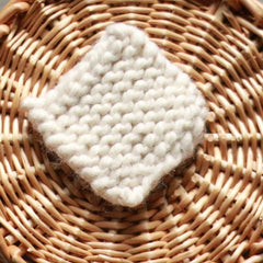Makeup remover scrubbie pad, off-white knitted square, set in a woven basket