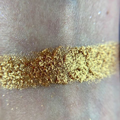Close-up of fingers applying shimmery bronze eyeshadow from the Harvest Moon palette to eyelid