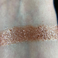 Close-up of fingertips applying shimmery bronze eye shadow from palette to eyelid