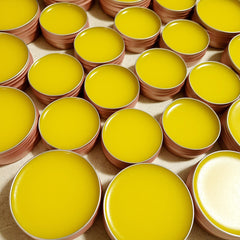 Lip balms, yellow glossy balm in round metal tins, arranged in a grid pattern