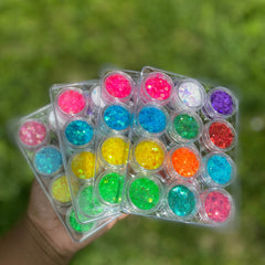 Side view of 12 iridescent glitter pots with rainbow hues in clear round containers, showcasing reflective shimmer