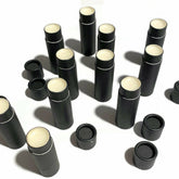 Lip balm tubes, black cardboard, white lip butter, scattered arrangement