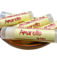 Lip balm tubes with yellow labels, Amaretto text, and Blue Poppy Bath & Body brand, in a wooden bowl