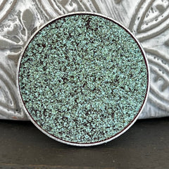 Close-up of holographic tea green eyeshadow with multi-chrome color shift in pressed pan