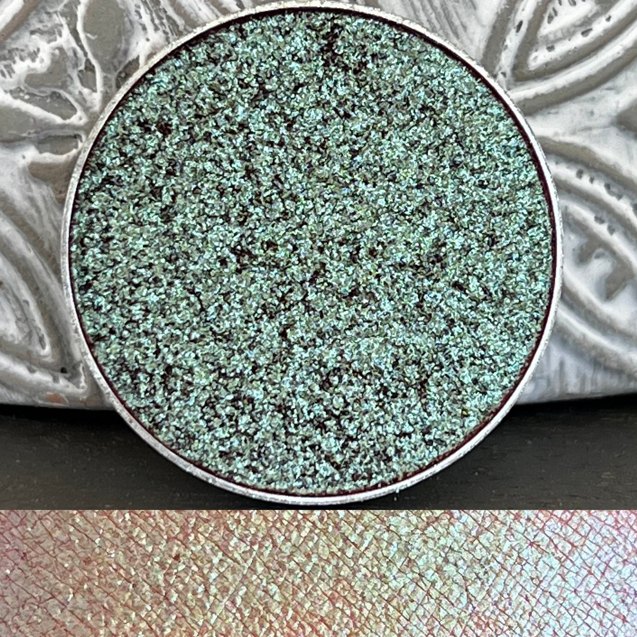 Pressed pan holographic eyeshadow with shifting tea-colored multi-chrome finish in round compact